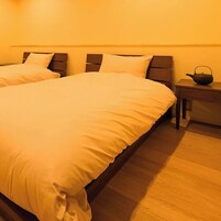 Una habitación de hotel con una cama grande, una mesita de noche con hervidor y suelo de madera.