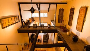 Un interno moderno con una scala in legno, un soppalco con ringhiera e calligrafia asiatica tradizionale sulle pareti.