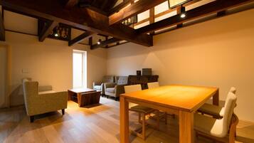 A spacious room with a wooden dining table and chairs, a sofa, and a small wooden cabinet.