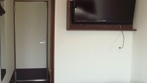 A hotel room with a large bed, a flat-screen TV mounted on the wall, and a door leading to another room. - Single Inn Niigata No.2 (Niigata)