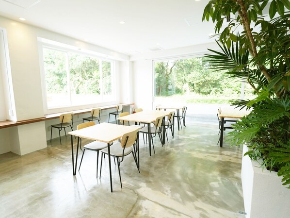 A spacious room with large windows, a long table, and chairs. - Oise Sun Cafe & Hotel (Hyuga)