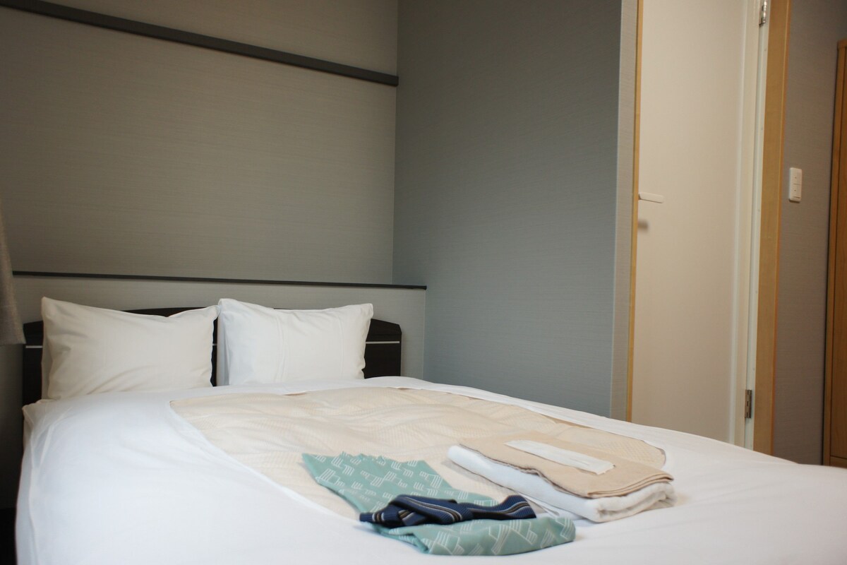 A neatly made bed with pillows, a folded blanket, and a folded towel.