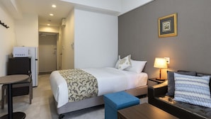Une chambre d’hôtel comprenant un lit, une table de chevet, une lampe et une petite table avec une chaise.