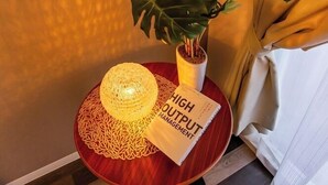 Una mesa con una lámpara decorativa, una planta en maceta y un libro titulado 'HIGH OUTPUT MANAGEMENT'.