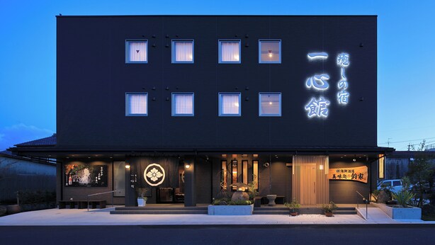 Een modern gebouw met een donkere gevel, veel ramen en verlichte reclameborden.