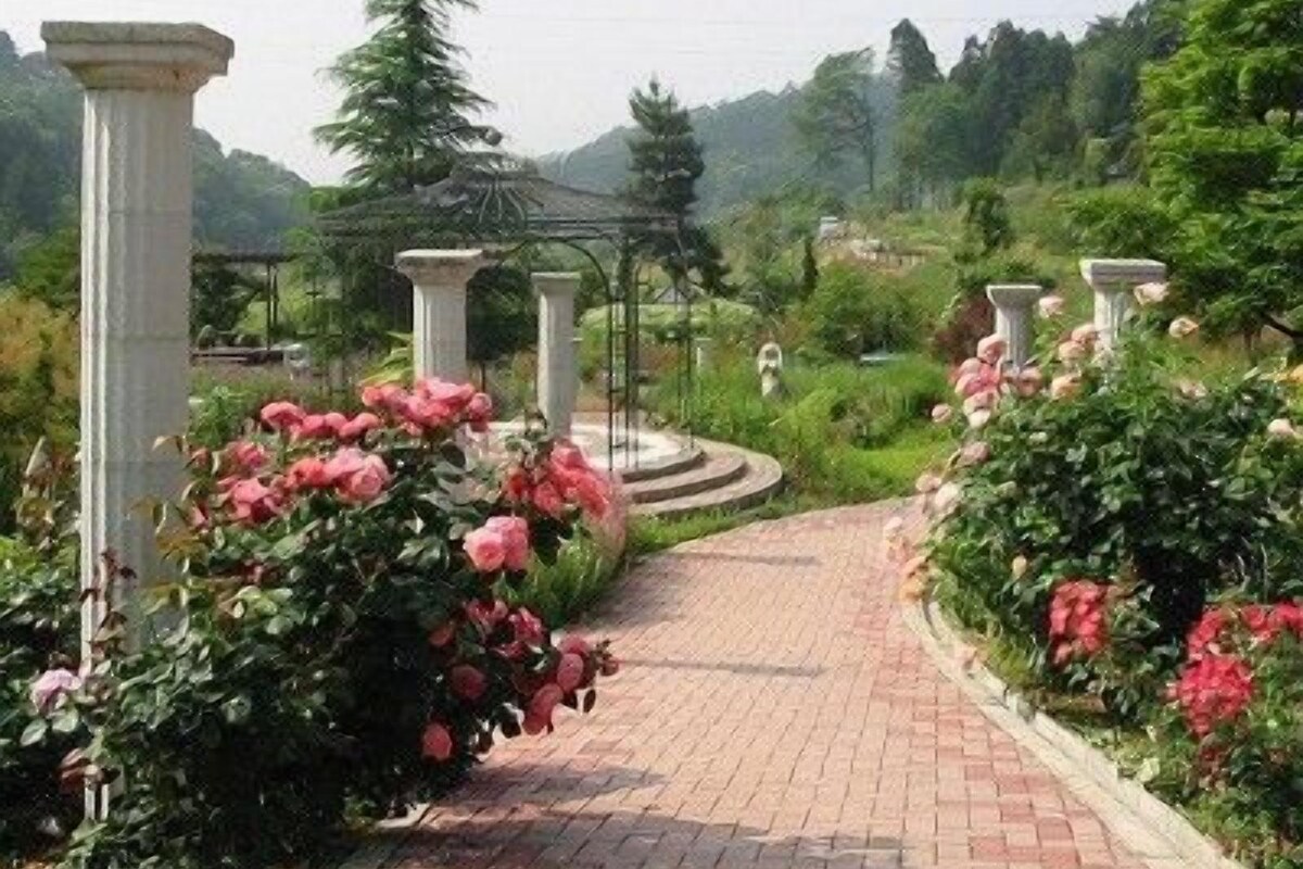 Un camino pavimentado con columnas blancas y flores rosadas.