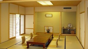 A traditional Japanese room with tatami flooring, a low table, and a television set.