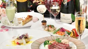 A dining table with various dishes, wine glasses, and a bottle of champagne.