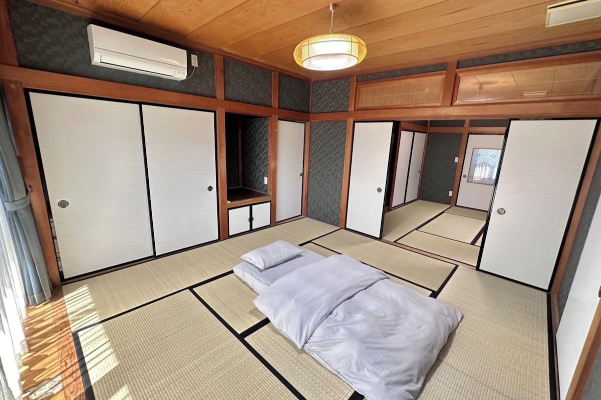 A traditional Japanese room with tatami flooring, sliding doors, and a ceiling fan.