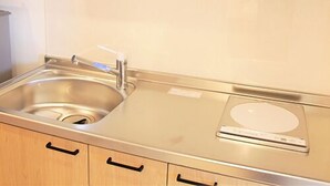 A kitchen with a stainless steel sink, a built-in oven, and wooden cabinets.