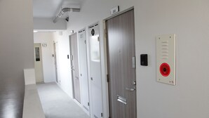 A hallway with doors numbered 2, 203, and 204, a fire alarm panel, and a ventilation system.