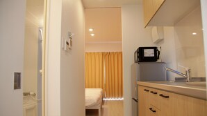 A compact kitchenette with a microwave, sink, and wooden cabinets.