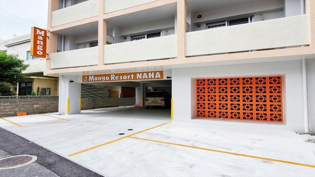 A building with a sign reading "Mango Resort NAHA" and a parking area with marked spaces.