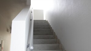 A staircase with a handrail, leading to a landing with a light source.