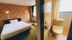 A hotel room with a bed, a wooden herringbone wall, a small bedside table, and a toilet. - Tabist Hotel Miyakonojo Miyazaki (Miyakonojo)