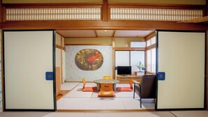 A traditional Japanese room with tatami flooring, a round table, a television, and sliding doors. - Sakana Asobi No Yado Yamacho (Fukui)