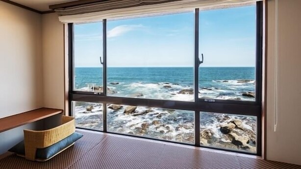 A room with a large window overlooking a rocky coastline.