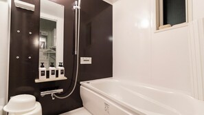 A bathroom with a bathtub, a shower, and a shelf with toiletries. - Ocean Front Maezato (Ishigaki)