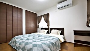 A bedroom with a large bed, a wardrobe, a bedside table, and an air conditioning unit.