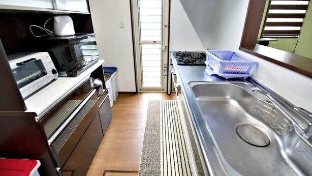 A compact kitchen with a microwave, toaster, and gas stove.