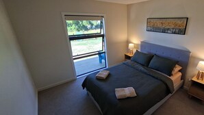 Una camera da letto con un letto, due comodini con lampade, una finestra e un quadro appeso al muro.