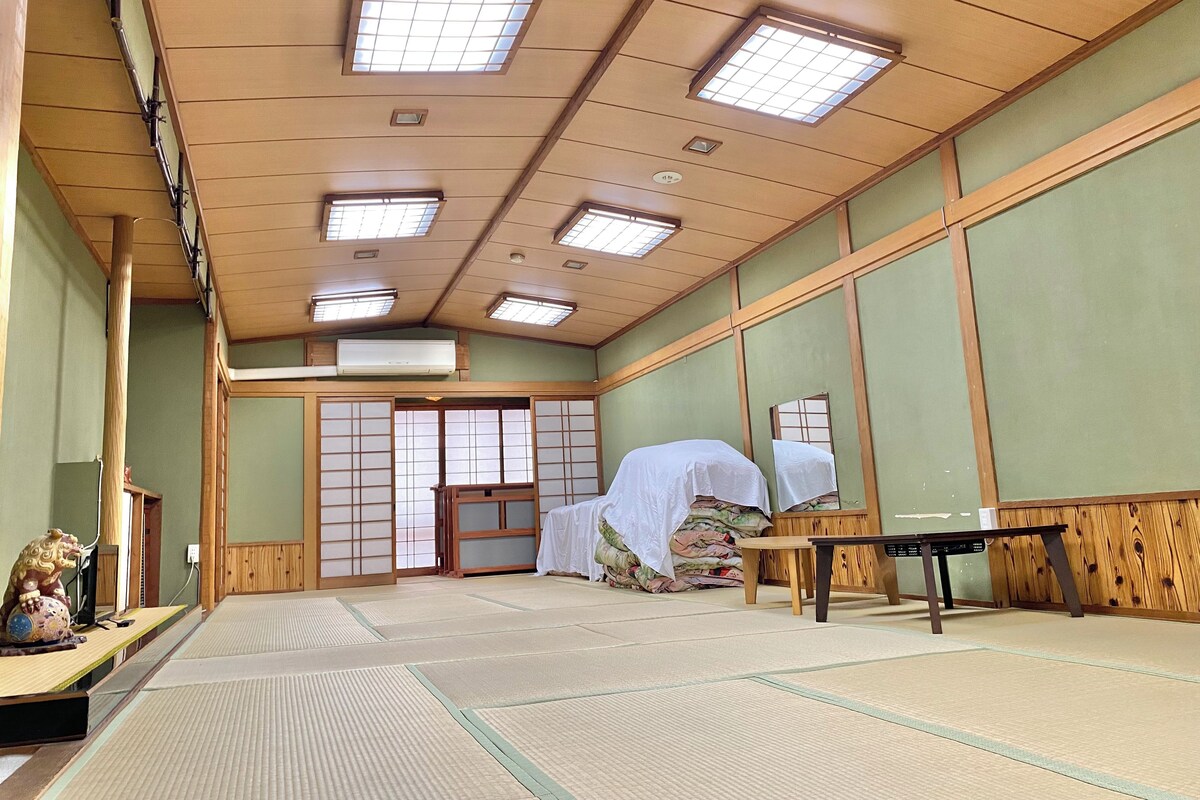 A traditional Japanese room with tatami flooring, sliding doors, and a ceiling with multiple light fixtures.