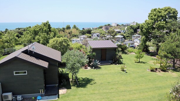A residential area with houses, a grassy yard, and a view of the sea.