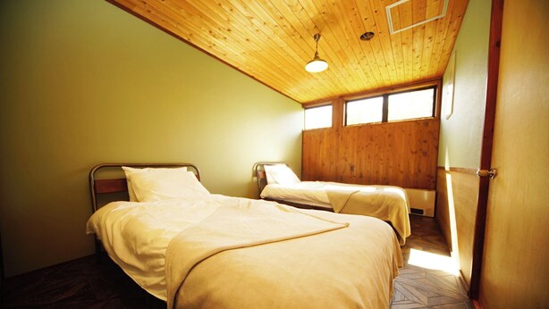 Une chambre avec deux lits, un plafond en bois et de grandes fenêtres.