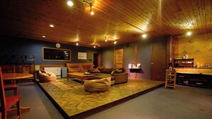 Un salon chaleureux avec un plafond en bois, un canapé, une table basse et un coin repas comprenant une table et des chaises.