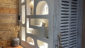 A wooden wall with built-in shelves and a small table with a vase of dried flowers. - Villa Luxury Lagoon - Aix en Provence (Ventabren)