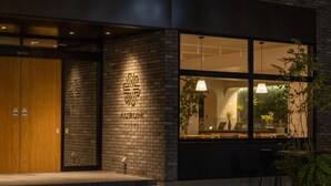 A modern building with a wooden door, a glass entrance, and a logo on the wall. - Aurum Misawa (Misawa)