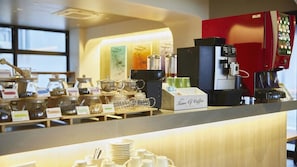 Una estación de café con una máquina de café, una exhibición de granos de café y un letrero que dice 'Time of Coffee'.