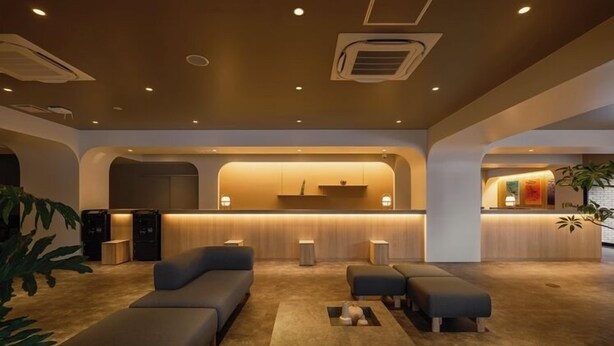 A modern hotel lobby with a central reception desk, seating area, and a plant. - Aurum Misawa (Misawa)
