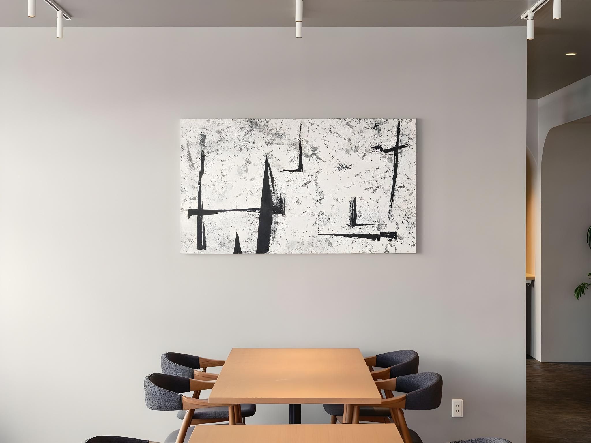 A modern interior with a minimalist table and chairs, a large abstract painting on the wall, and a visible electrical outlet.