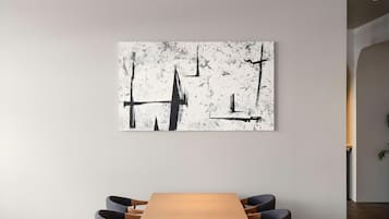 A modern interior with a minimalist table and chairs, a large abstract painting on the wall, and a visible electrical outlet.
