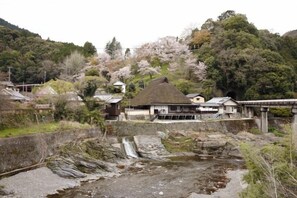 Un pueblo rural con casas tradicionales, un puente de piedra y una pequeña cascada.