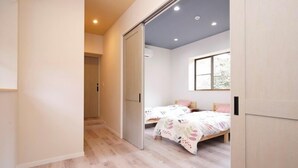 Quarto com duas camas, uma porta deslizante e uma janela com vista.