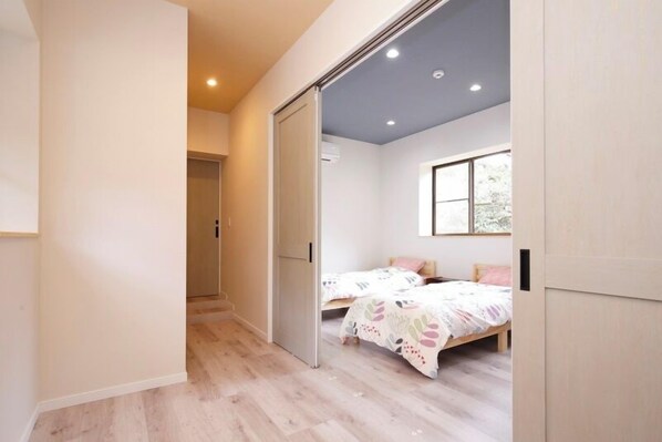 Un dormitorio con dos camas, una puerta corredera y una ventana con vistas.