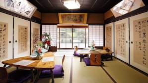 Um quarto japonês tradicional com tatames, mesinhas baixas e almofadas roxas.