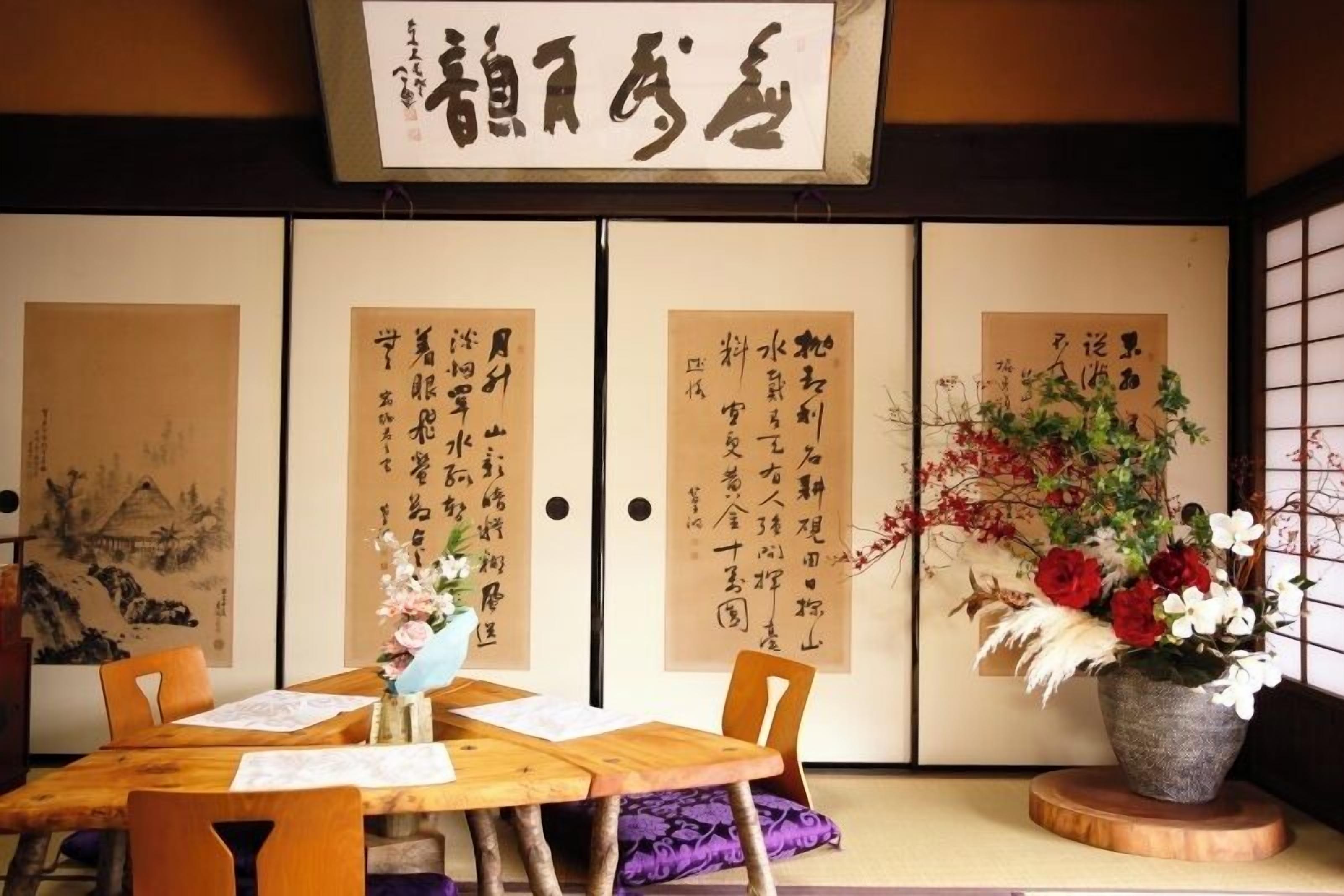 A traditional Japanese room with tatami flooring, a low wooden table, and a sliding door with calligraphy.