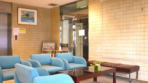 A lobby with a blue sofa set, a glass coffee table, and a bench. - Hotel Mates Ageo (Ageo)