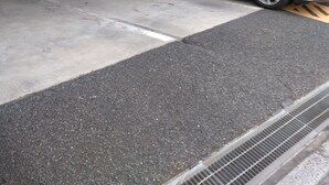 A parking garage with a car parked inside, concrete walls, and a tiled floor. - Hotel Mates Ageo (Ageo)