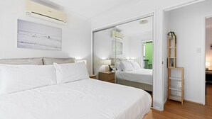 Un dormitorio con una cama grande, una mesita de noche, un espejo y un armario.