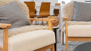 Una sala de estar acogedora con sofás amplios color crema y sillones de madera, dispuestos alrededor de una mesa de centro.