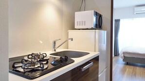Una cocina compacta con estufa a gas, microondas y pileta.