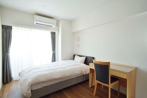 Une chambre d’hôtel équipée d’un lit, d’un bureau et d’un appareil de climatisation.