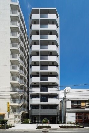 Un immeuble à plusieurs étages doté de balcons, un ciel dégagé et une rue en contrebas.