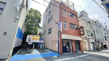 Un edificio de varios pisos con un estacionamiento al frente, un toldo azul y un letrero con un personaje de caricatura.