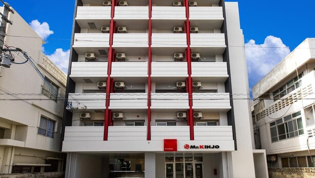 A multi-story building with a Mr. KINJO restaurant at the ground level, featuring a modern design with red accents and air conditioning units. - Mr. Kinjo Link in Kume Naha (Naha)
