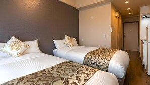 A hotel room with two beds, a dark wall, a door, and a refrigerator. - Mr. Kinjo Link in Kume Naha (Naha)